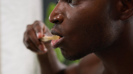 Moving shot African American male hold toothbrush with whitening toothpaste ethnic man brushing teeth cleaning gums oral care dentistry clean tooth refresh morning dental healthy hygiene in bathroomの写真素材