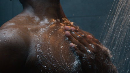 African American naked ethnic man bare wet guy washing body applying shower gel shampoo liquid soap...