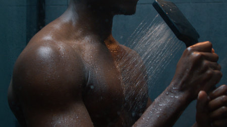 Muscular African American ethnic man showering singing in bathroom washing clean body falling hot...