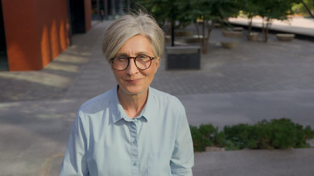 Smiling adult Caucasian businesswoman mature senior middle-aged gray-haired business woman happy 50s female walking up stairs in city outdoors confident going upward walk steps dreaming career successの写真素材