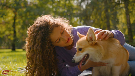 Happy girl playing with golden puppy on grass nature summer weekend female woman pet trainer love friend domestic animal outdoors in park hugging cute little dog pembroke welsh corgiの写真素材