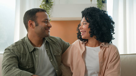 Happy parents African American mother father embrace cuddle on couch couple husband wife affectionate married girl guy smiling man woman anniversary wedding proposal love relationship family at homeの写真素材