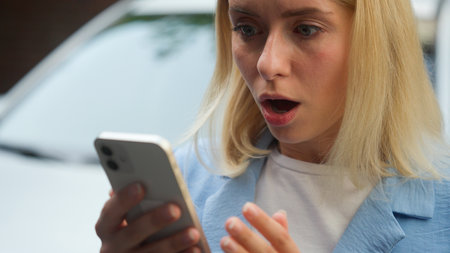 Shocked stressed frustrated Caucasian businesswoman girl client driver female buyer scroll screen mobile phone vehicle owner woman read bad news online in city automobile problem car rent difficultyの写真素材