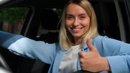 Happy Caucasian businesswoman female woman in car automobile owner seat belt safety girl driver smile demonstrating thumb up in city ride driving test drive auto renting transport buy vehicleの写真素材