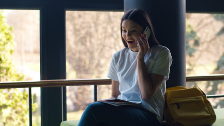 Caucasian student girl woman lady female pupil teen schoolgirl teenager at city outdoors campus school university college smiling happy talking mobile phone smartphone talk cellphone conversationの写真素材