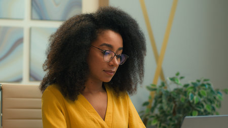 Smiling African American woman ethnic student businesswoman office manager employer typing laptop computer at workplace online chatting with clients concentrated business girl female browsing internetの写真素材
