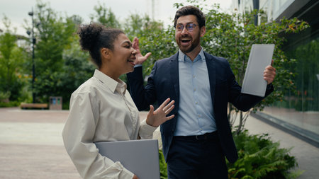 Two multiracial business colleagues multiracial African American woman girl female businesswoman talking happy carefree with Caucasian man guy male businessman walking in city go to office good newsの写真素材