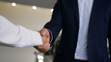 Two unrecognizable people in car salon hands close up Caucasian male client buyer man guy new automobile buying test drive bank credit handshaking woman dealer saleswoman female girl give key of autoの写真素材