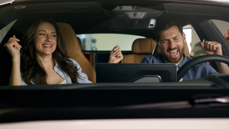 Happy dancing funny moving to music radio technology audio stereo system inside car Caucasian couple in auto dance woman girl female girlfriend with man guy male boyfriend travel joy automobile autoの写真素材