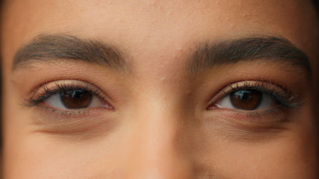 Close up human eyes Latina Hispanic girl woman beauty female face part details open eye dark eyeball looking at camera health medical care eyelid vision eyesight makeup eyelashes portrait gaze indoorsの写真素材