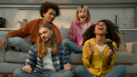 Multiracial diversity friends playing console together fun laughing Caucasian women men support...