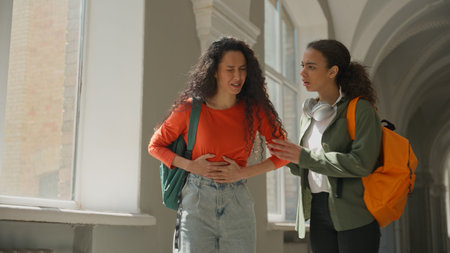 Two students girl Hispanic women Latina female friends in university college walking talking woman...