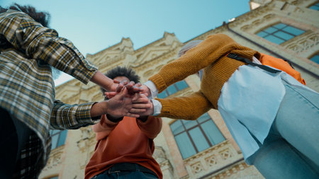 Happy laugh multiracial friends three students multiethnic girls Caucasian female women African American male guy man in city in college university stack hands teamwork cooperation friendship gestureの写真素材