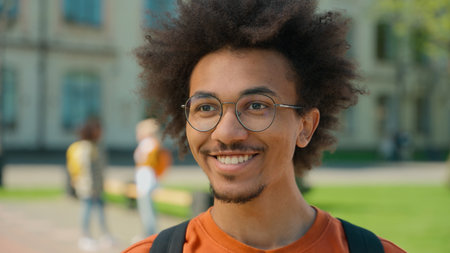 Portrait happy smiling positive ethnic African American man male student guy smiling looking at camera education learning study near university campus college high school outdoors satisfied studyingの写真素材