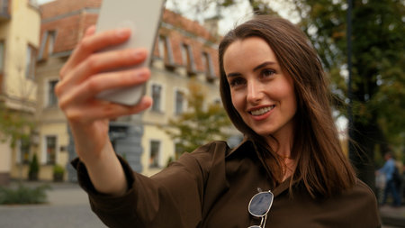 Smiling Caucasian woman female businesswoman business girl in city street outside holding mobile...