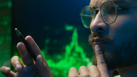 Arabian Indian man analyst programmer holding pen pointing coder hacker work planning male pondering thinking imagination businessman calculating contemplation strategy guy inspiration solve businessの写真素材