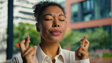 African American woman female girl businesswoman portrait crossed fingers hope dream wish gesture hopeful pray wishing waiting results worried aspirations business city outdoor entrepreneur employerの写真素材