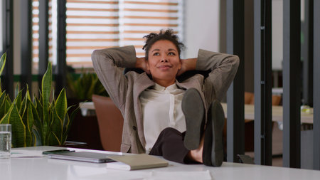 Relaxed businesswoman African American employer business woman girl female office worker close laptop online computer work done relax lean on chair put legs on table enjoy rest break end working dayの写真素材