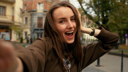 Mobile phone camera view happy smiling Caucasian woman posing smiling make selfie at street female girl in city holding smartphone video call record vlog photo picture online live broadcasting streamの写真素材