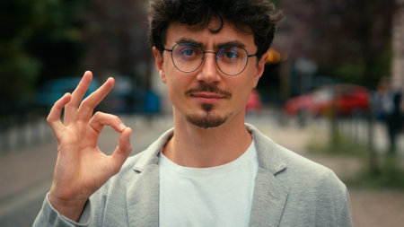 Close up portrait Hispanic business man male guy showing ok gesture in city male guy in glasses show okay sign fine good result excellent reaction outdoors at street businessman recommend joyful gladの写真素材