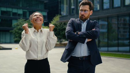 Happy successful smiling celebrating win African American woman businesswoman female in city joyful Caucasian man male businessman different emotions two business colleaguesの写真素材