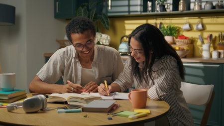 Multiethnic couple girl guy African Indian students high school university teenage man woman studying together writing home kitchen think idea brainstorm solution success high five cooperate teamworkの写真素材