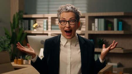 Joyful celebrate victory in office happiness winning smile successful business triumph Caucasian senior woman middle-aged businesswoman mature female employer yelling screaming happy rejoice amazingの写真素材