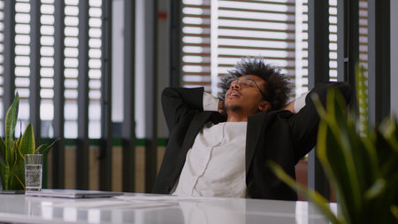 African American ethnic business man businessman guy male employer entrepreneur work online at office working typing computer stop job break close laptop relax hands behind head finished complete taskの写真素材