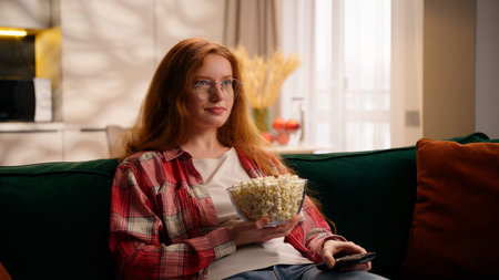 Young Caucasian woman teen girl watching TV changing channels television films show amazed say wow...