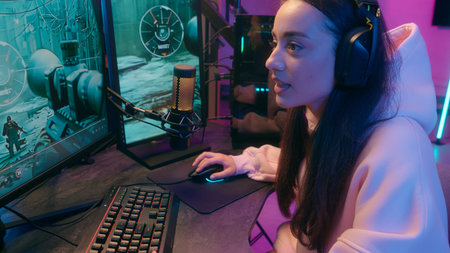 Caucasian addicted dependence female gamer girl woman streamer play at computer internet virtual gaming at home web battle online playing video game at evening talking with microphone and headsetの写真素材