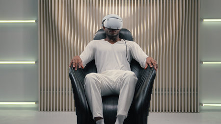 African American gamer guy male man put on virtual reality headset 3d VR helmet indoors playing...