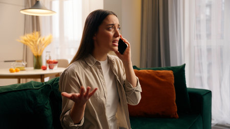 Angry furious stressed European girl female woman bad call phone mobile conversation trouble talking arguing argument conflict communicate smartphone at home annoyed speaking cellphone in apartmentの写真素材