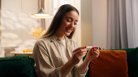 Smiling positive healthy health medicine concept rejoice happy Caucasian woman female girl lady celebrate pregnant news at home holding pregnancy test joyful celebrating fertility childbirth babyの写真素材