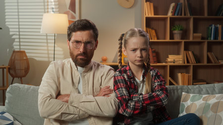 European family problem father with daughter offended sad upset angry annoyed dad man crossed hands quarrel bad relationship with adopt custody little disappointed child kid daughter girl at homeの写真素材