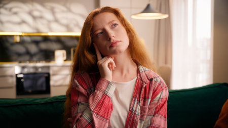 Pensive woman thinking at home creative girl think solution planning decide idea indoors female puzzled at couch in living room creating decision confused hesitate deciding question solving portraitの写真素材