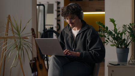 Glad Hispanic guy worker using laptop at home man freelancer typing computer programmer work remote job developer browse web male in headphones playing virtual game online hipster shopping on Internetの写真素材