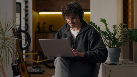 Glad Hispanic guy worker using laptop at home man freelancer typing computer programmer work remote job developer browse web male in headphones playing virtual game online hipster shopping on Internetの写真素材