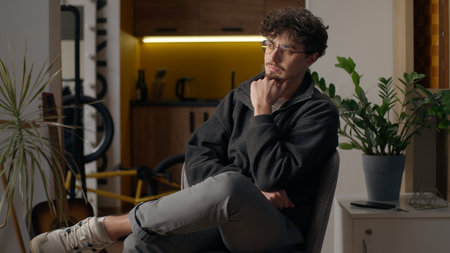 Pensive Caucasian guy adult hipster sitting thinking at home contemplative man lost in thoughts search idea pondering doubtful thoughtful male in eyeglasses relax dreaming think indoors contemplatingの写真素材