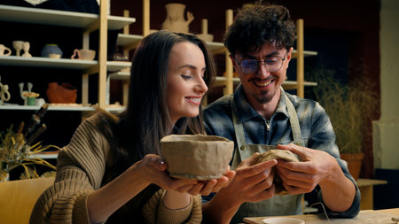 Caucasian woman man teacher student in pottery workshop handmade craft hobby potter teaching sculpture ceramics clay modeling couple date girl guy have fun laughing creating crockery in art studioの写真素材
