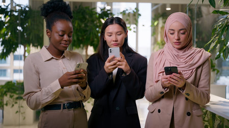 Three diverse multiracial business women mobile phones businesswomen African Asian Muslim girls...