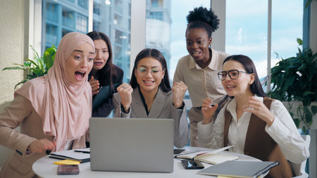 Excited shocked multiethnic women females businesswomen team colleagues multiracial group looking laptop computer celebrating win shock business offer deal success applause indoor office meeting roomの写真素材