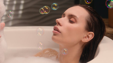 Sensual beautiful peaceful relaxing Caucasian woman female girl lady foamy bath at home bathroom foam soapy bubbles touching hands washing bathing spa stress recreation hygiene procedure shower gelの写真素材