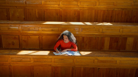 Distant view Caucasian girl student Hispanic woman Latina American female in university college auditorium high school academy writing task homework test exam write in classroom study education learnの写真素材