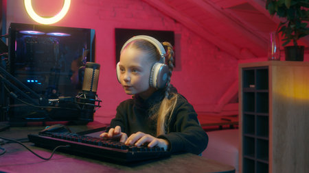 Concentrated gamer little girl user enjoy late evening streaming talking to microphone daughter kid child playing computer virtual video online gaming car auto driving modern game streamer at homeの写真素材