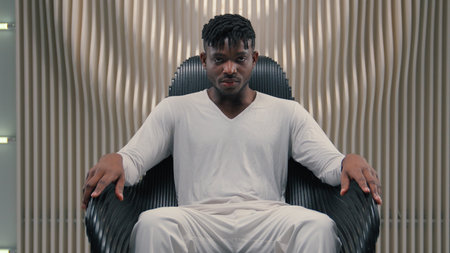 Futuristic confident serious gamer programmer hacker African American man guy male sitting in chair in futurism modern room studio in chair looking at camera 3D computer graphics AI network conceptの写真素材