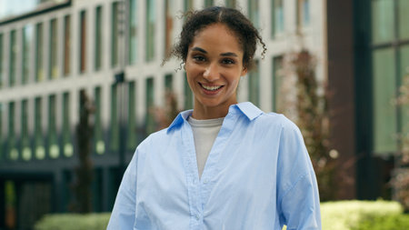 Carefree satisfied African American woman female girl glad businesswoman business lady employer entrepreneur real estate trader in city outdoors looking at camera smiling downtown building work smileの写真素材