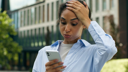 African American business woman user ethnic girl female lady businesswoman student entrepreneur looking mobile phone reading bad news problem trouble stress lost failure online hold smartphone in cityの写真素材