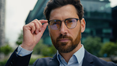 Portrait serious Caucasian man businessman business male guy manager employer entrepreneur boss leader in city downtown looking at camera touch eyeglasses glasses eyesight vision problem health styleの写真素材