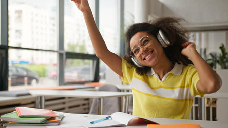 Happy funny dancing moving dance African American girl female student business woman listen music in headphones enjoy audio wireless earphones in cafe school university library college studying pauseの写真素材