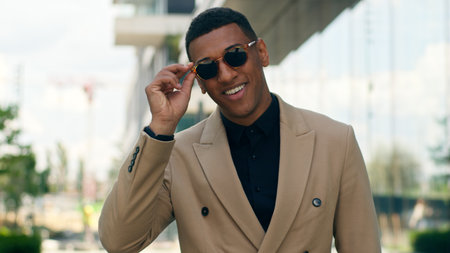 Smiling stylish fashionable confident African American business man posing in city outdoors wearing black sunglasses businessman guy male entrepreneur smile at camera in eyewear style fashion happyの写真素材